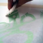 Applying sticker to surface using squeegee