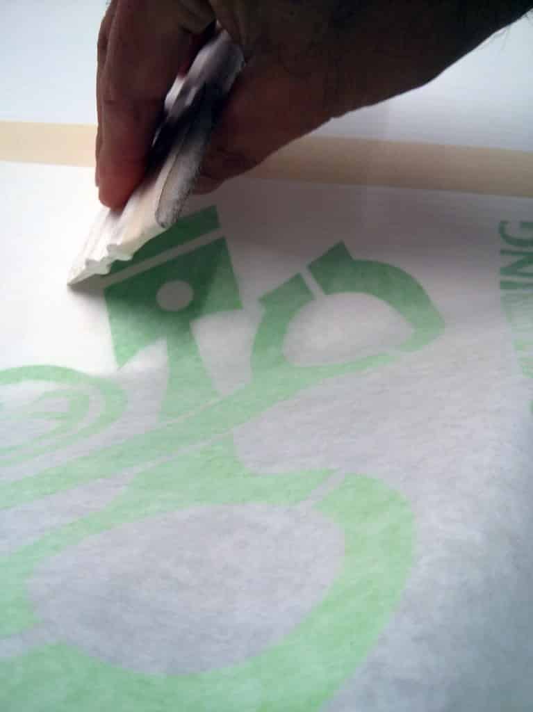 Applying sticker to surface using squeegee